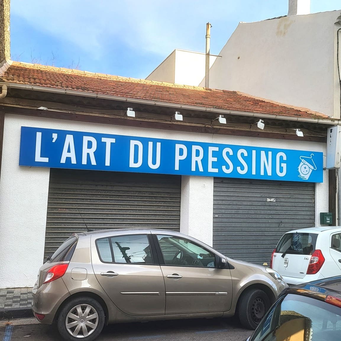 Enseigne bleue avec le texte "L’ART DU PRESSING" en lettres blanches