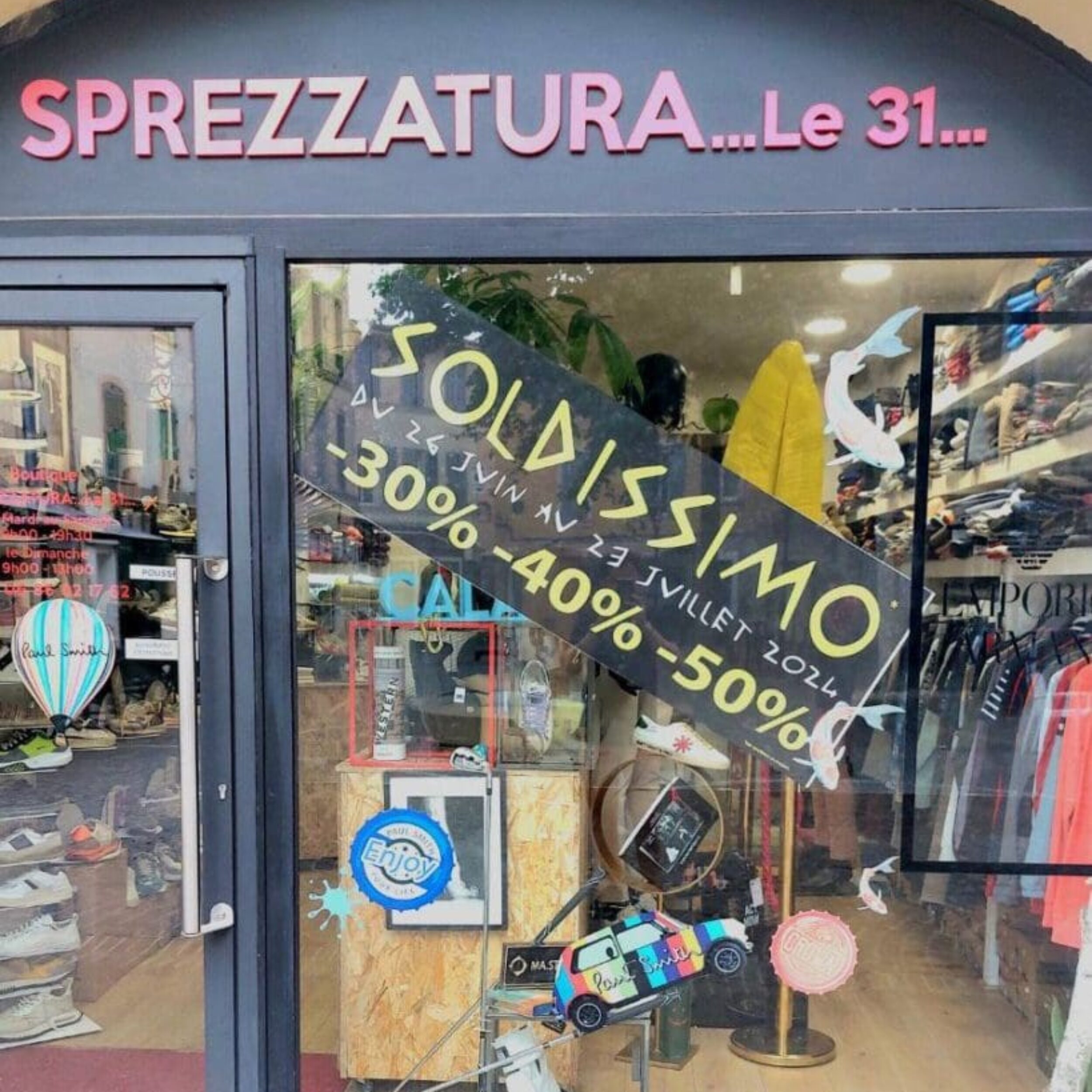 Vitrine du magasin Sprezzatura à Martigues avec un grand autocollant noir en diagonale affichant « SOLDISSIMO » et les réductions de 30%, 40% et 50%.