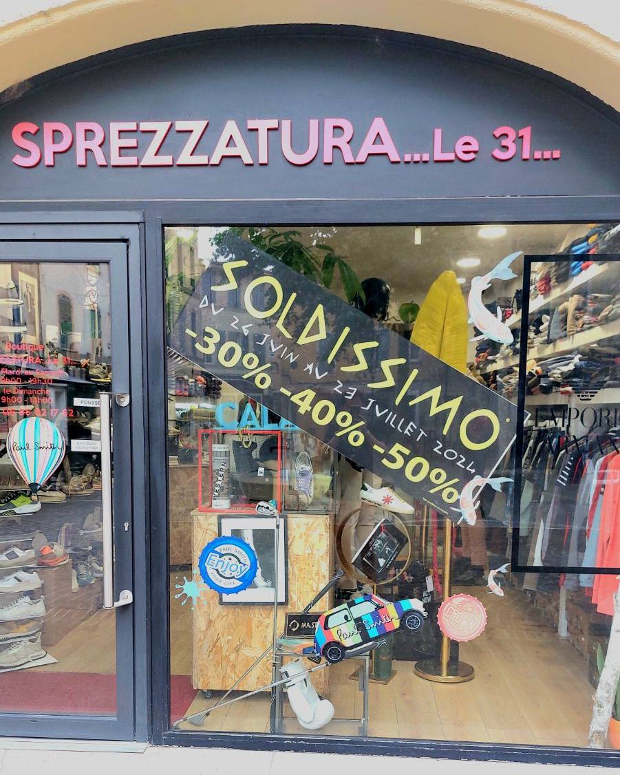 Vitrine du magasin Sprezzatura à Martigues avec un grand autocollant noir en diagonale affichant « SOLDISSIMO » et les réductions de 30%, 40% et 50%.