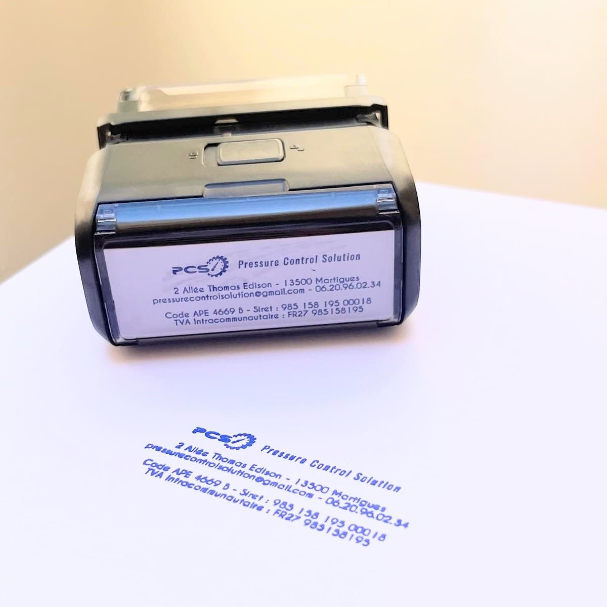Tampon encreur noir avec impression bleue du logo PCS et des coordonnées complètes de l’entreprise Pressure Control Solution.
